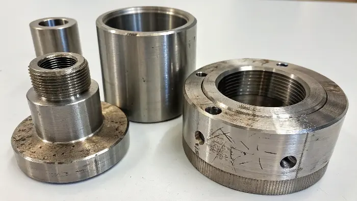 A CNC milling machine cutting a stainless steel part, with visible coolant spray