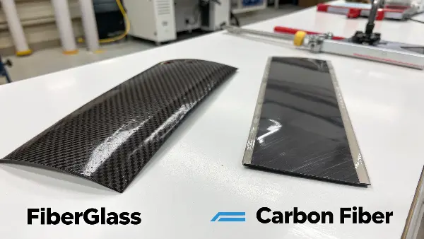 A pile of carbon fiber raw tow next to a roll of fiberglass mat, with price tags to show the difference